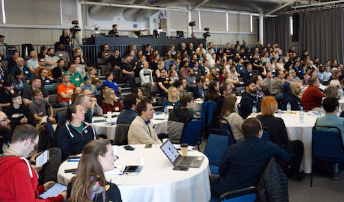 A crowd of people sat down in a conference room listening to a speaker.