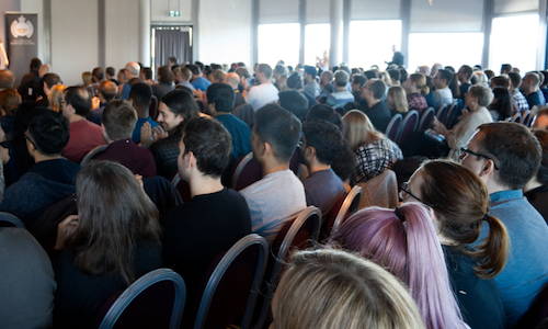 A crowd of people sat down in a conference room listening to a speaker.