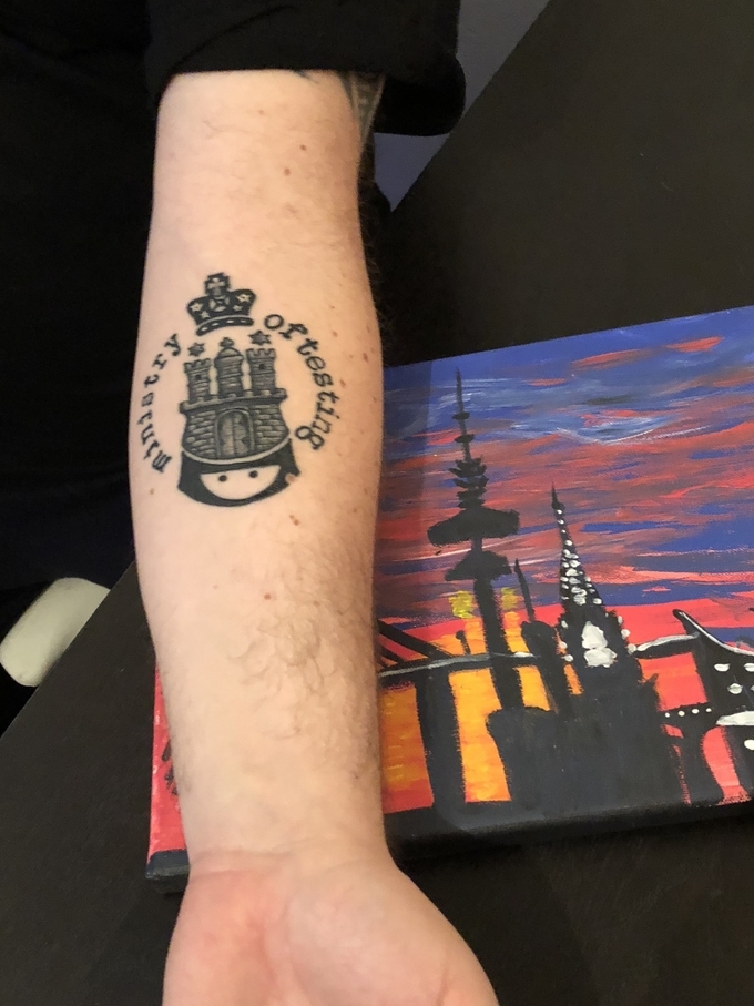 A photo of an arm with a Ministry of Testing logo tattoo as part of a castle image